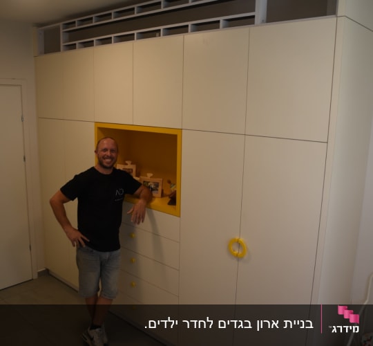 נגר עומד ליד ארון עם ידיות צהובות